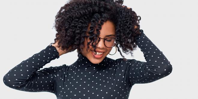African American female smiling broadly with her hands in her beautiful, healthy hair.